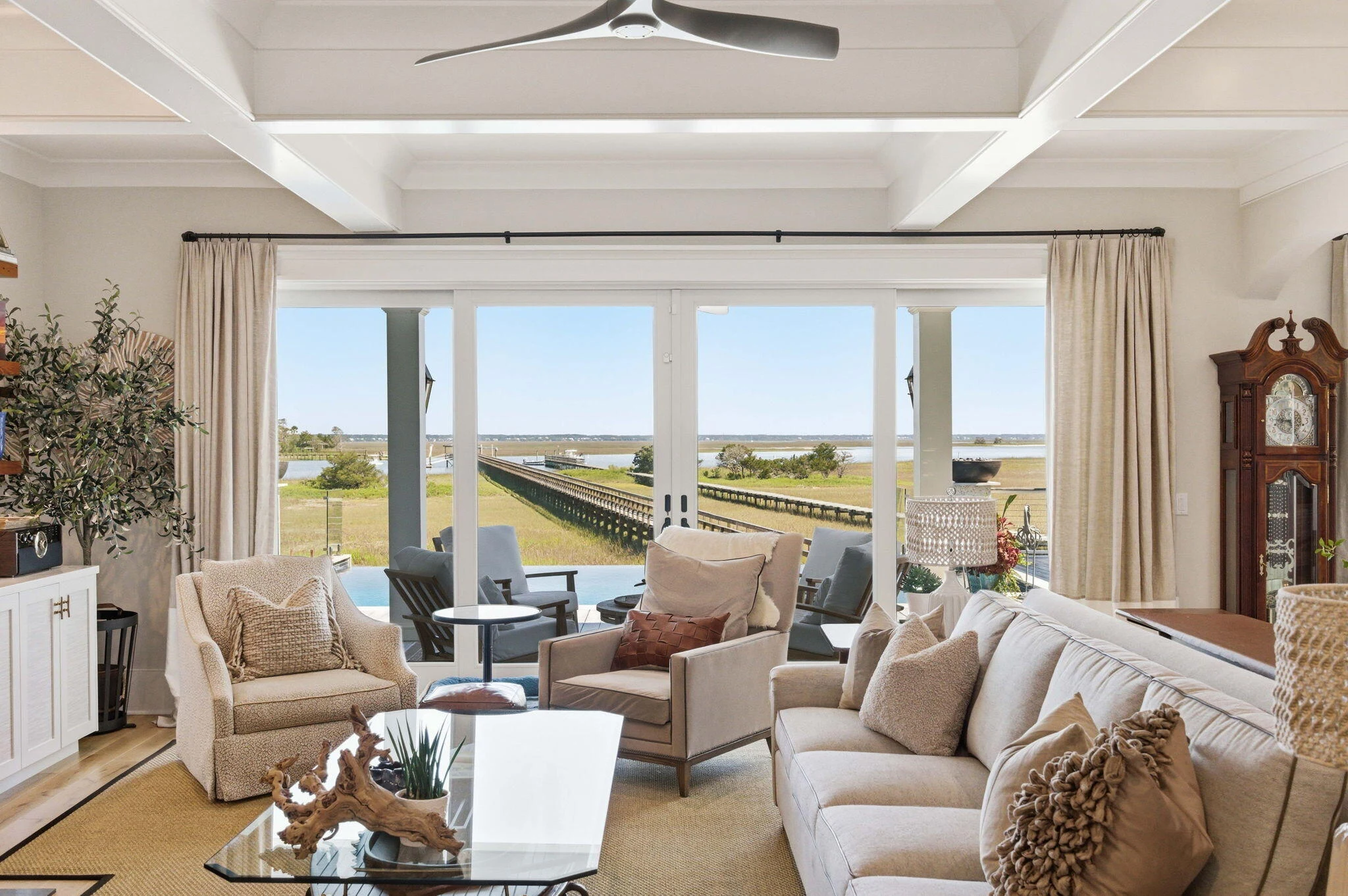 Coffered living room with glass doors framing the waterfront view