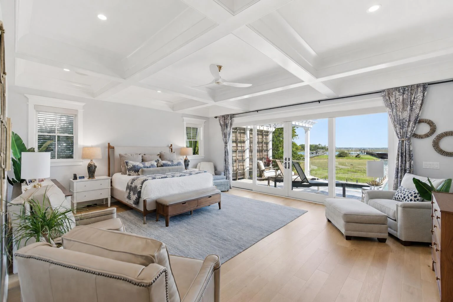 Primary bedroom with seating area and doors opening toward the waterfront terrace